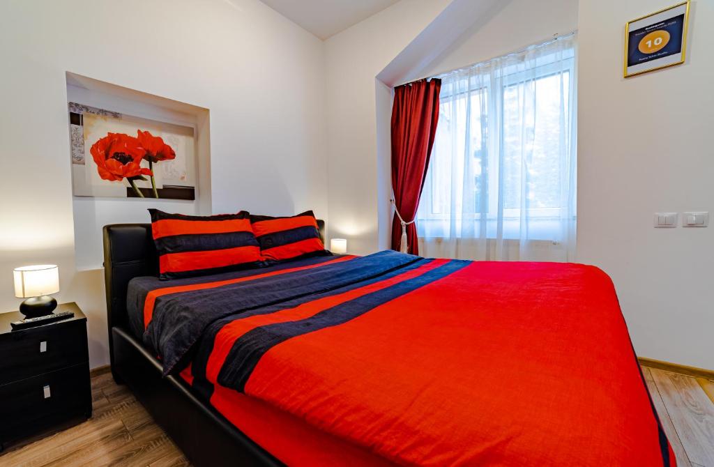 una camera da letto con un letto con una coperta rossa e una finestra di Poarta Schei Studio a Braşov