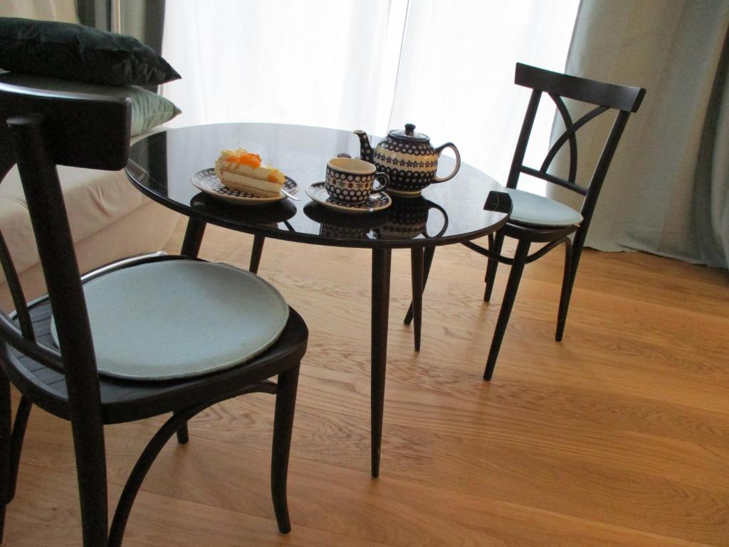 2 Stühle und ein Tisch mit einem Teller Essen drauf. in der Unterkunft Apartment am Apfelbaum in Reutlingen