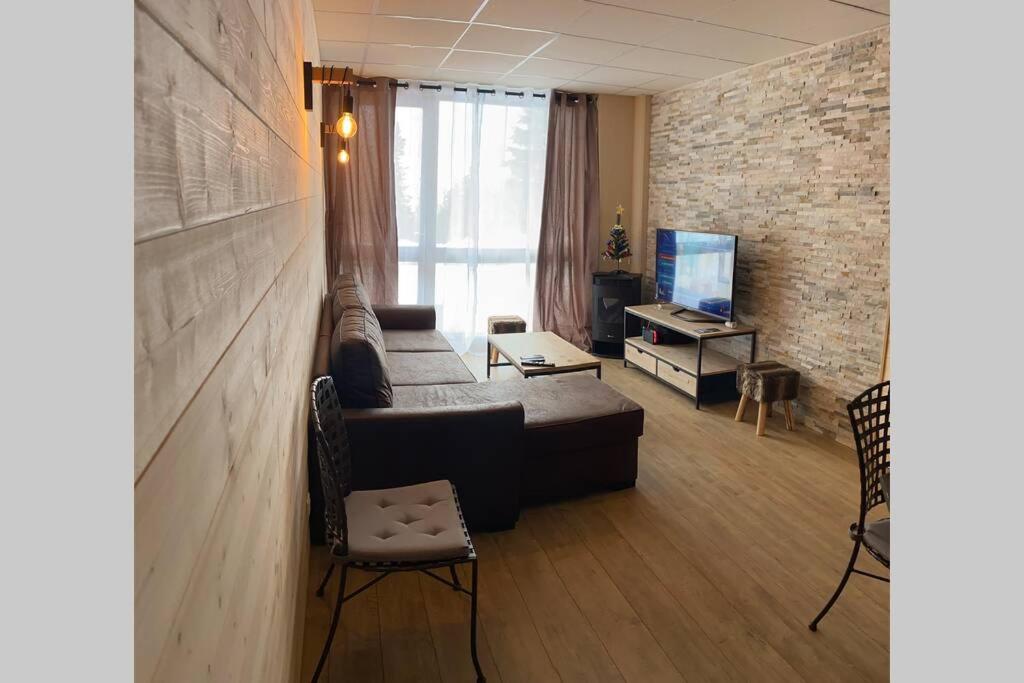 ein Wohnzimmer mit einem Sofa und einem TV in der Unterkunft Le refuge des marmottes in Chamrousse