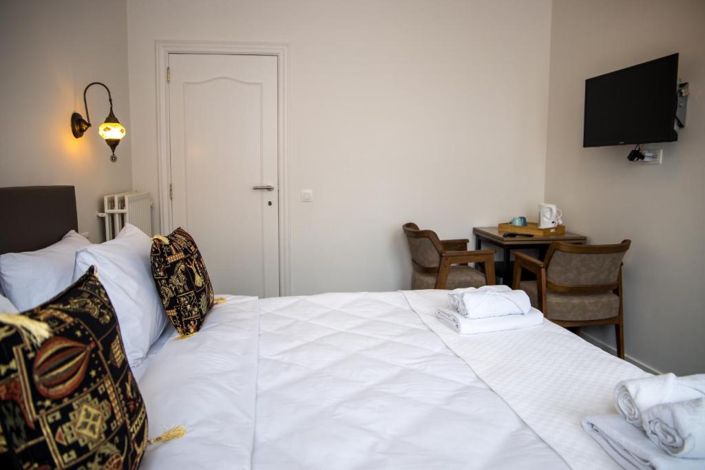 a bedroom with a white bed with a table and a television at Hotel Guzy in Lier