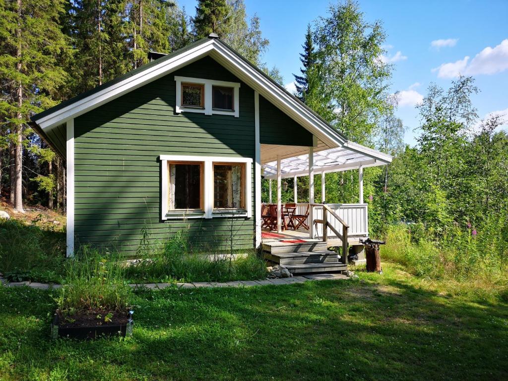 ein kleines grünes Haus mit einer Veranda auf einem Rasen in der Unterkunft Lakeside cottage Metsäranta Savonranta in Savonranta