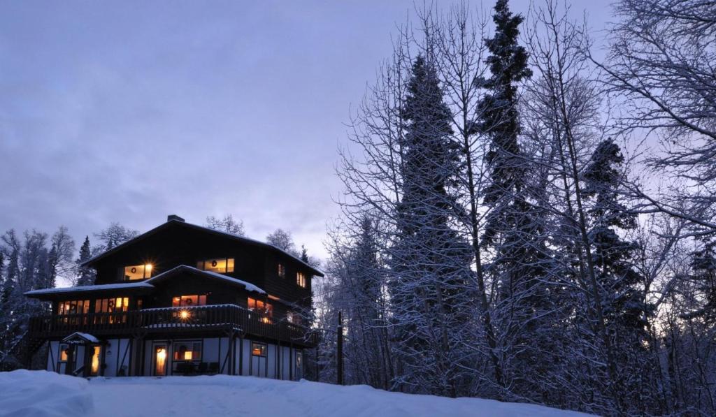 une grande maison dans la neige la nuit dans l'établissement Talkeetna Chalet, à Talkeetna