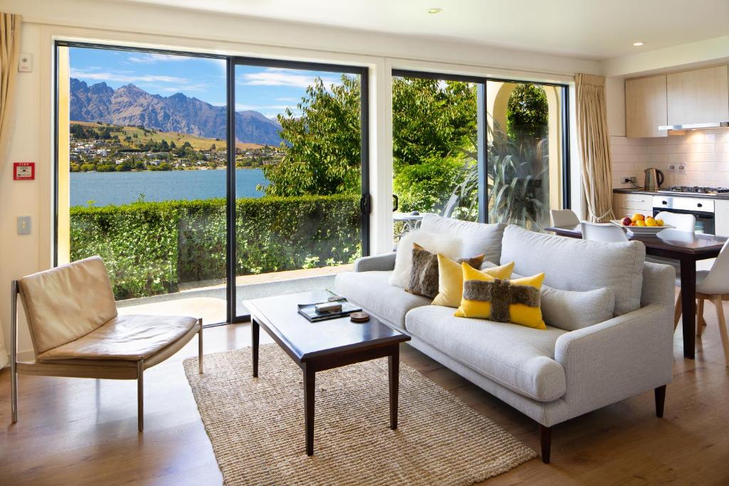 a living room with a white couch and a large window at Villa Del Lago in Queenstown