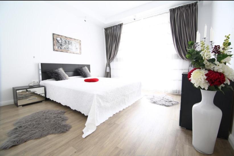 a bedroom with a white bed and a vase of flowers at Casa Bella in Ştefăneştii de Jos