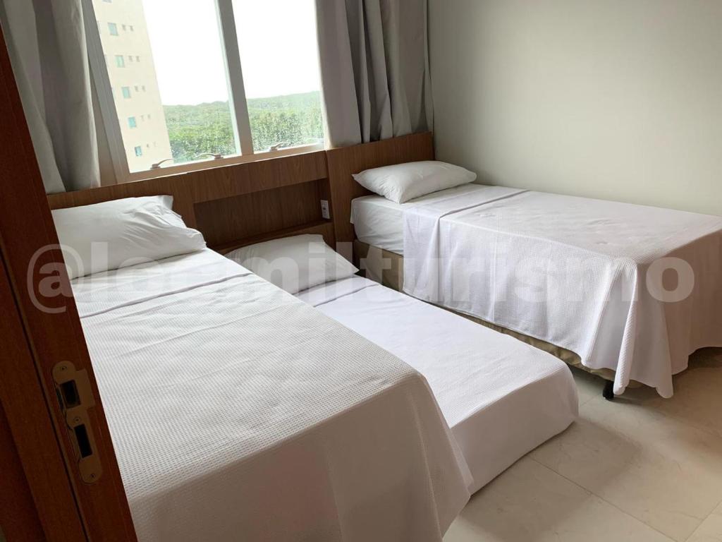 2 Betten in einem kleinen Zimmer mit Fenster in der Unterkunft Apartamento em Resort - Exclusive in Salinópolis