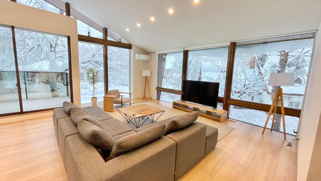 a large living room with a couch and a tv at Ahiru Chalet by Hakuba White Fox Company in Hakuba