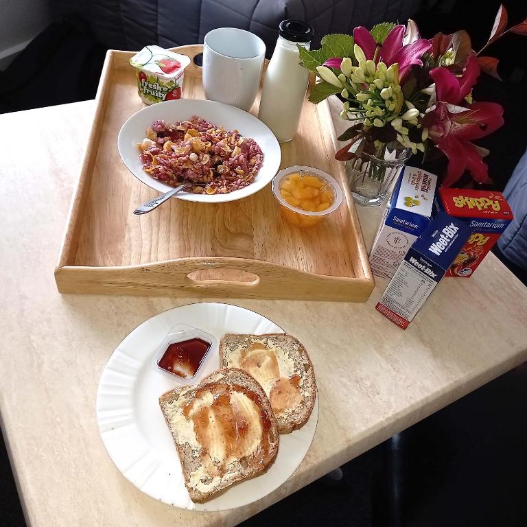 a table with a tray with a plate of bread and a plate of food at Alexander Motel in Taumarunui