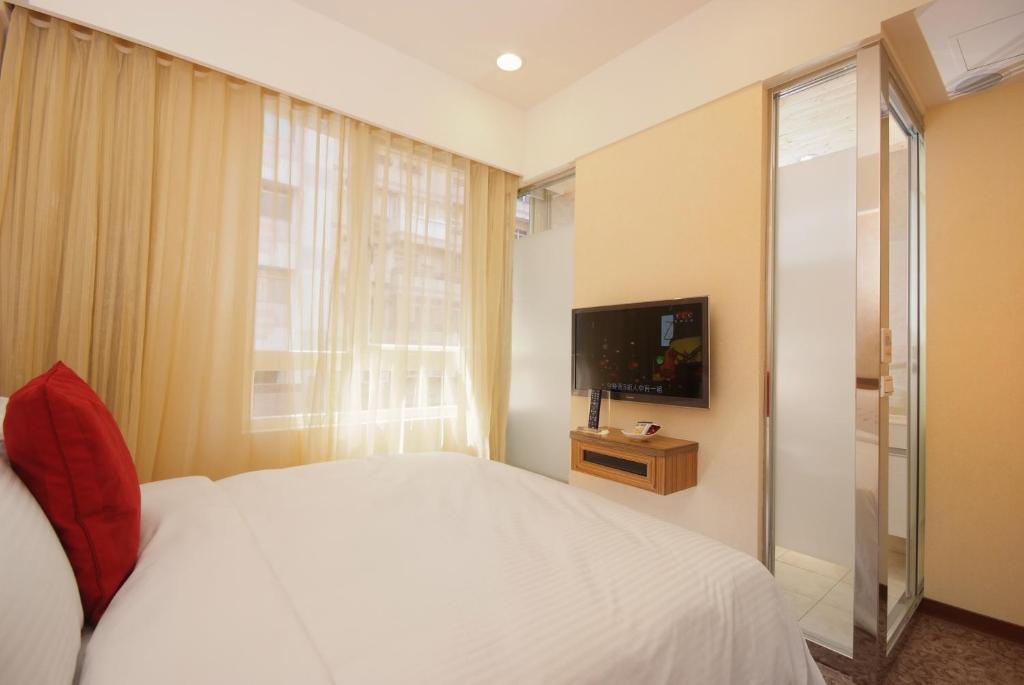 a bedroom with a white bed and a television at Golden Hotel in Taipei