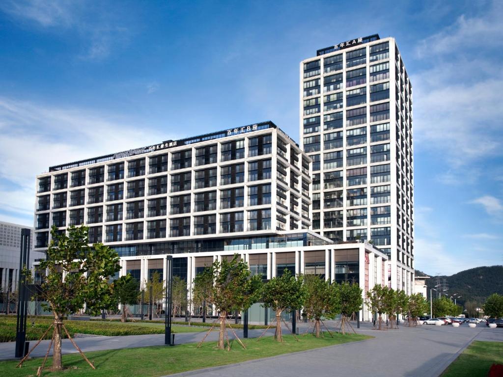 un alto edificio bianco con alberi di fronte di Howard Johnson Parkland Hotel Dalian a Dalian