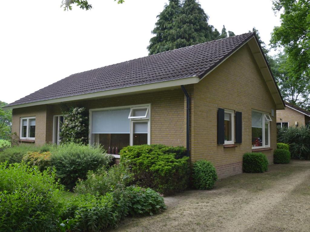 uma casa castanha com um telhado preto e arbustos em Rural holiday home wildlife spotting Achterhoek em IJzerlo