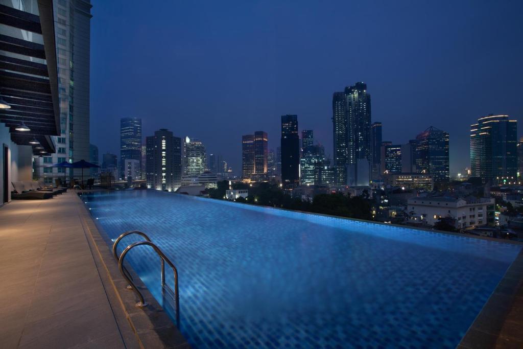 a swimming pool with a city skyline at night at Somerset Sudirman Jakarta in Jakarta