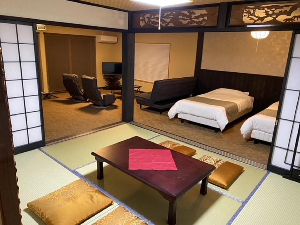 a room with a bed and a table and a room with a bed at お宿 勝 in Nagiso