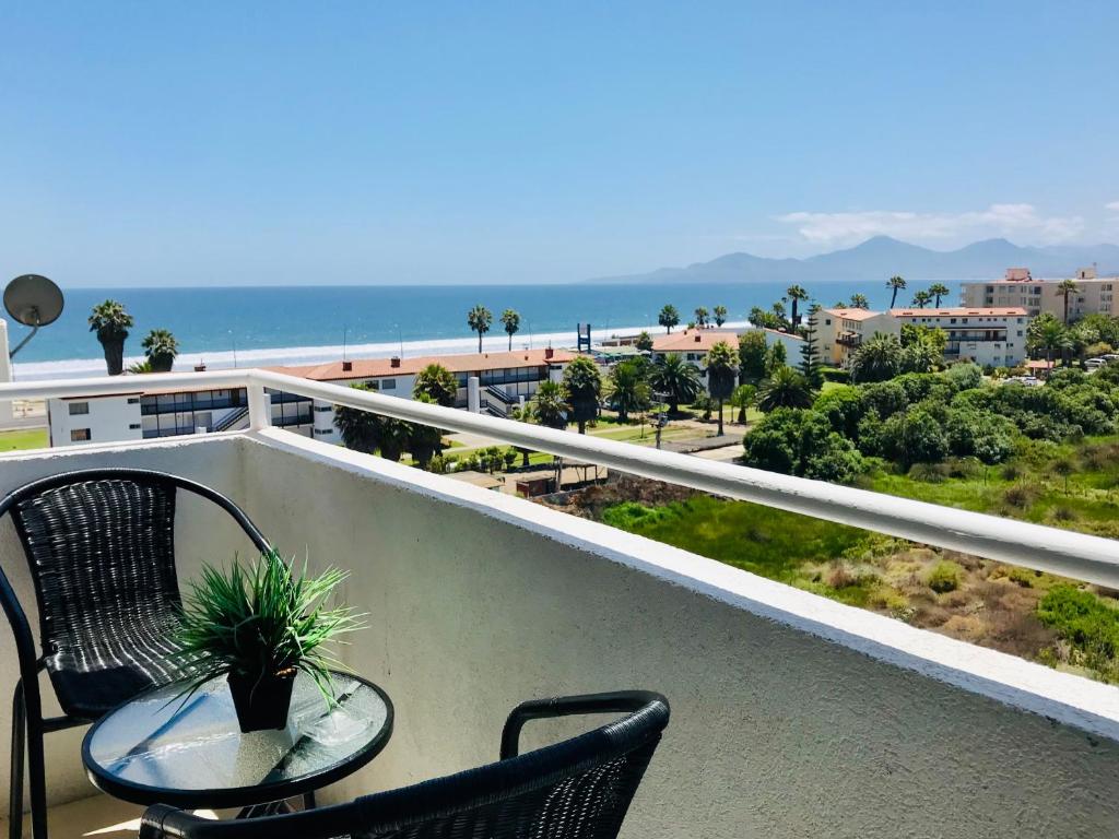 balcón con mesa, sillas y vistas al océano en Nicoland Playa y piscina La Serena, en La Serena