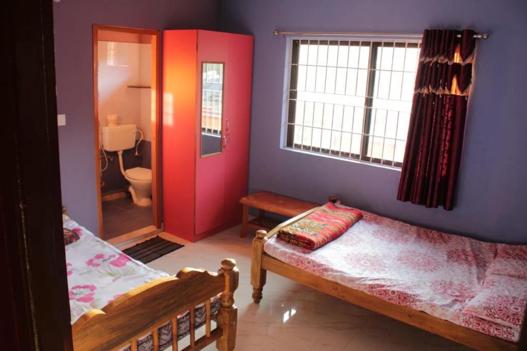a room with two beds and a red door at Vamoose Balgal Homestay in Kalasa