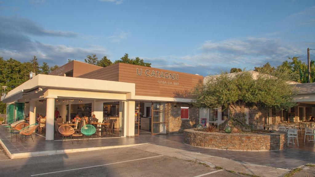 a store with tables and chairs in a parking lot at Hotel U Catagnu in San-Nicolao