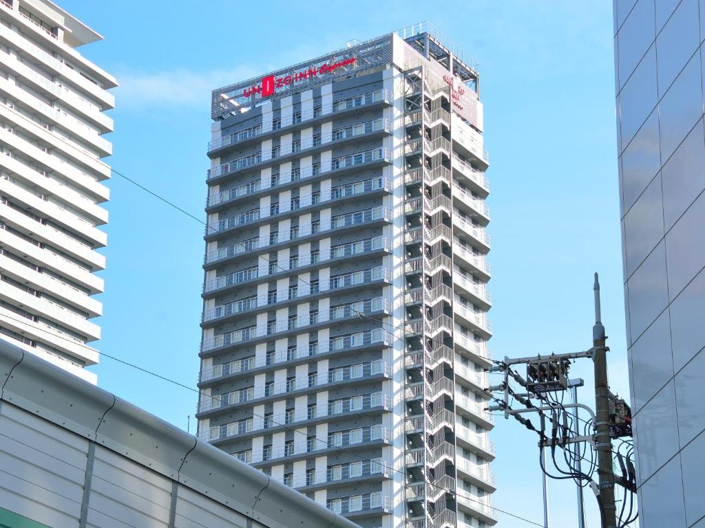 ein hohes Gebäude mit einem Schild darüber in der Unterkunft UNIZO INN Express Osaka Minamihommachi in Osaka
