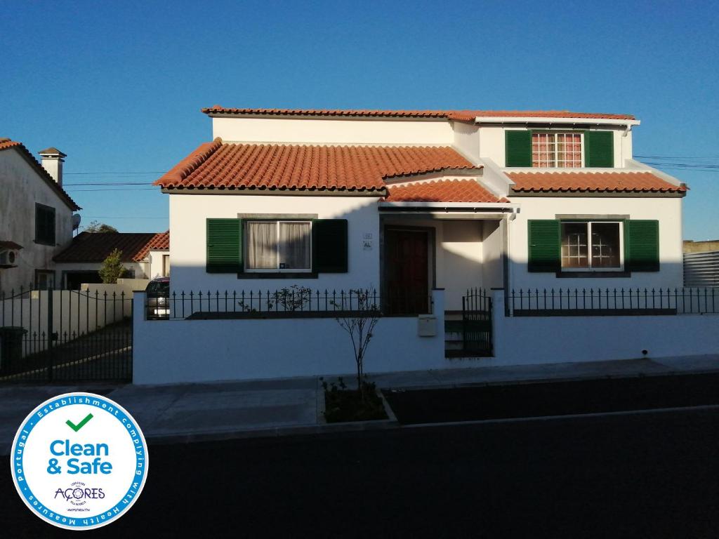 une maison blanche avec des fenêtres vertes et blanches dans l'établissement Pedro Sousa Rooms na Relva, à Ponta Delgada