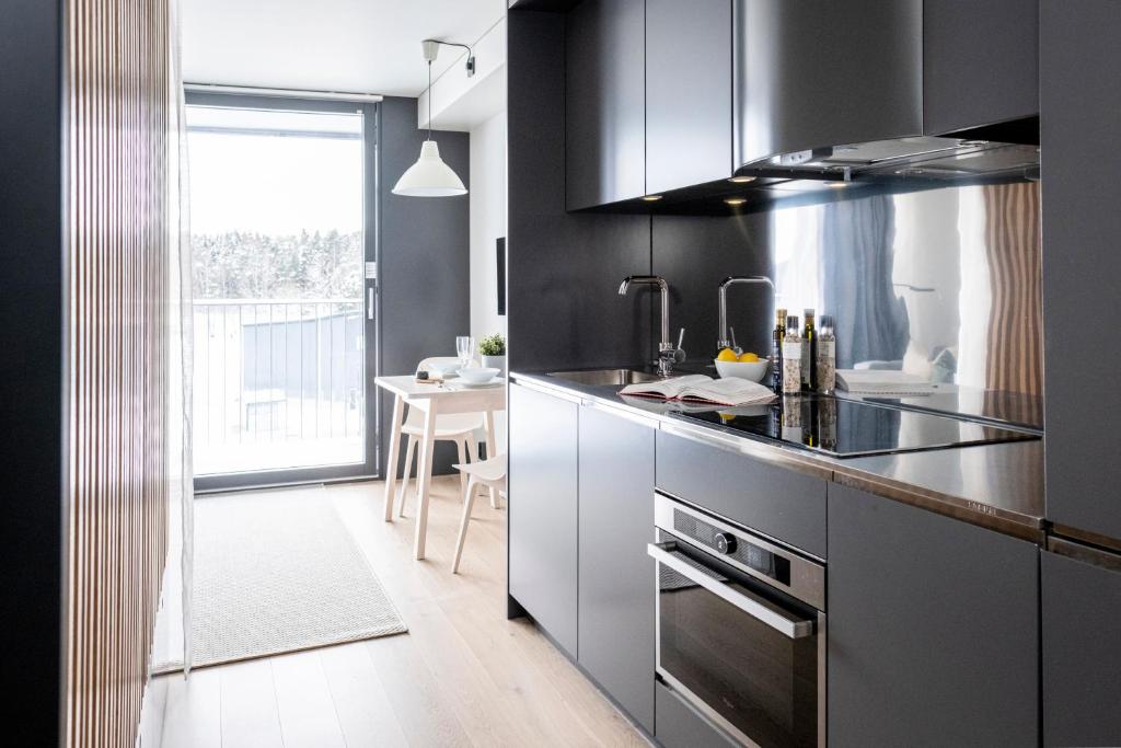 uma cozinha com armários pretos e uma mesa num quarto em HOOM Home & Hotel Järfälla em Järfälla