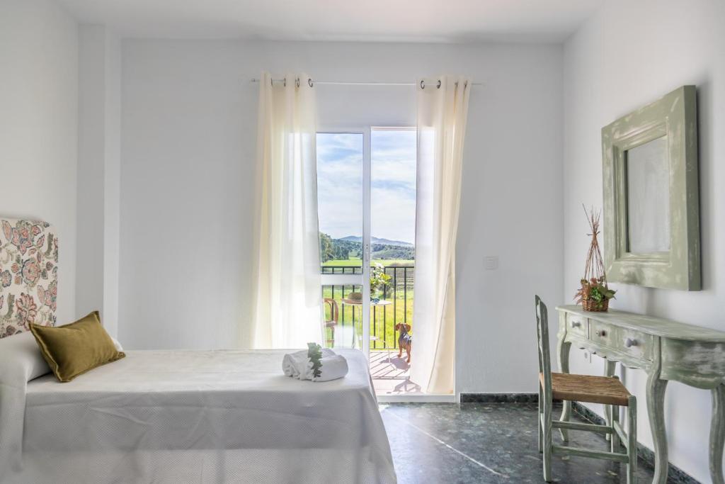 Dieses weiße Zimmer verfügt über ein Bett, einen Tisch und ein Fenster. in der Unterkunft Hotel Marhava in Conil de la Frontera