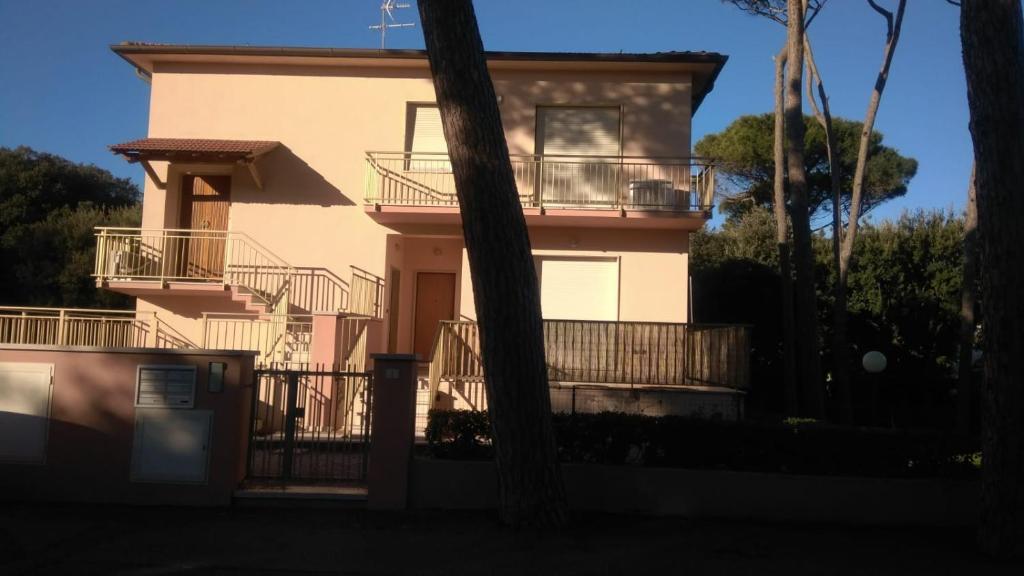 uma casa cor-de-rosa com varanda e árvores em appartamento Etrusco em San Vincenzo