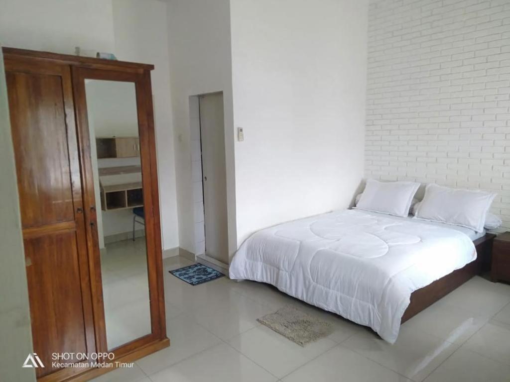um quarto com uma cama branca e um espelho em KoolKost @ Aisyah Residence (Minimum Stay 6 Nights) em Medan