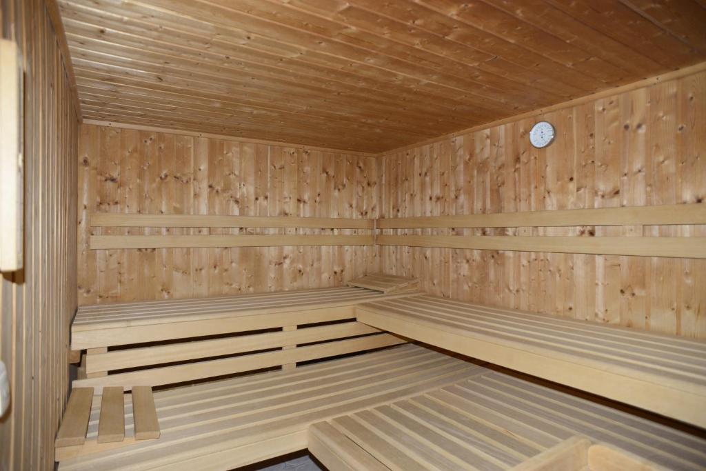 a wooden sauna with benches and a clock in it at Alpengasthof zur Post in Schattwald