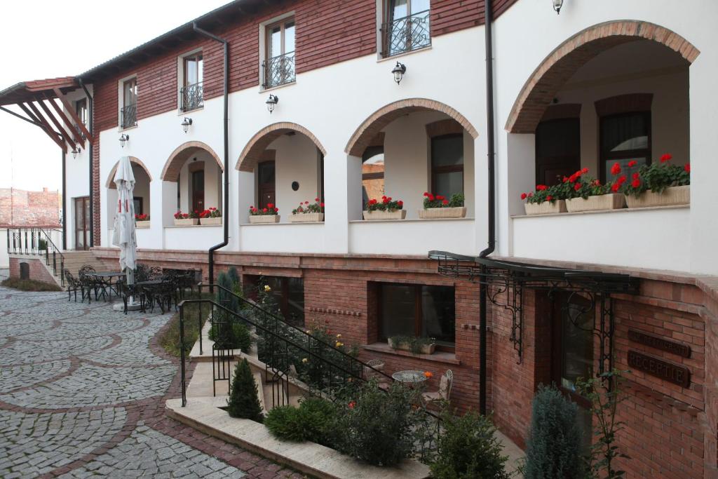 a building with a patio with red flowers in window boxes at La Maison de Caroline in Alba Iulia
