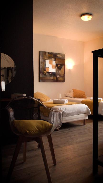 um quarto com duas camas e uma cadeira em Hotel Le Derby em Quimper