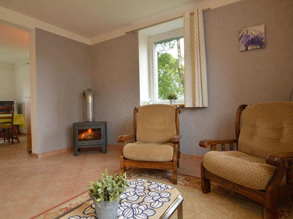 a living room with two chairs and a fireplace at Holiday Home with Garden Heating Barbecue in Butgenbach