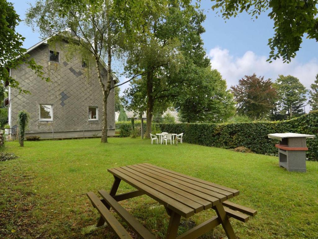 a wooden picnic table in a yard with a house at Holiday Home with Garden Heating Barbecue in Butgenbach