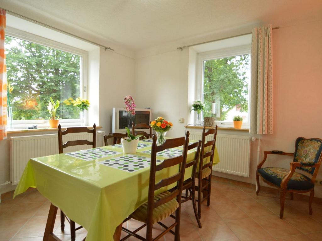 a dining room with a table and chairs and two windows at Holiday Home with Garden Heating Barbecue in Butgenbach