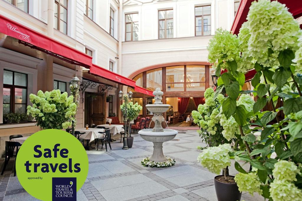 a courtyard with a fountain in a building with plants at Ekaterina Hotel in Saint Petersburg