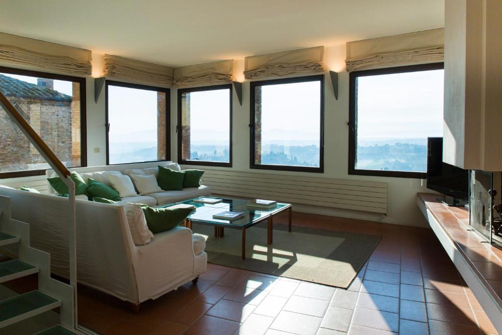 sala de estar con sofá, mesa y ventanas en Zafferano Rooftop Terrace Tower House, en San Gimignano
