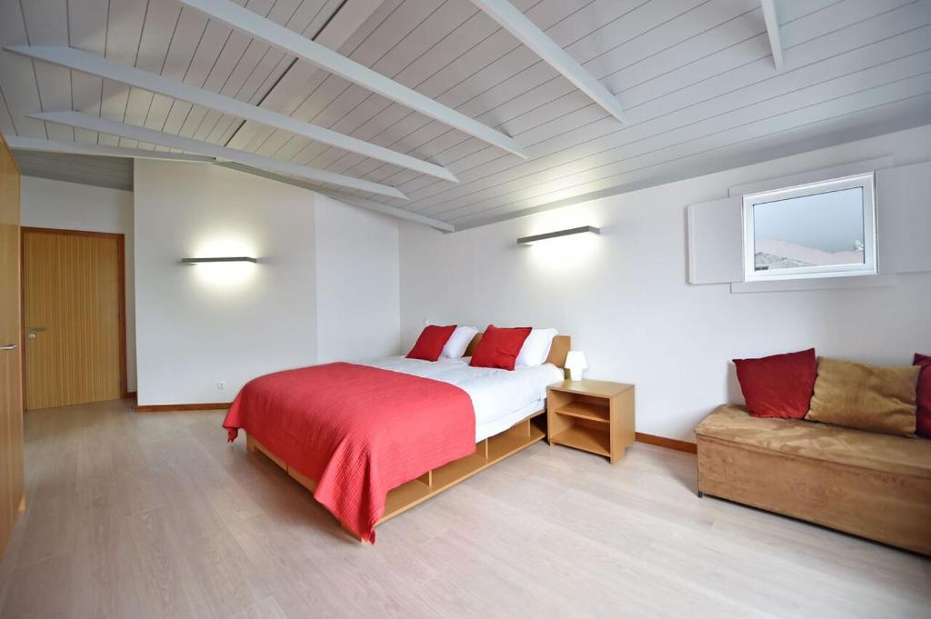 a bedroom with a large bed and a couch at Casa da Baía - Guest House in Horta