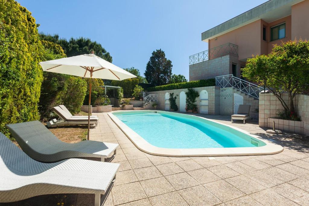 - une piscine avec 2 chaises et un parasol dans l'établissement Villa Primavera - Homelike Villas, à Capoterra