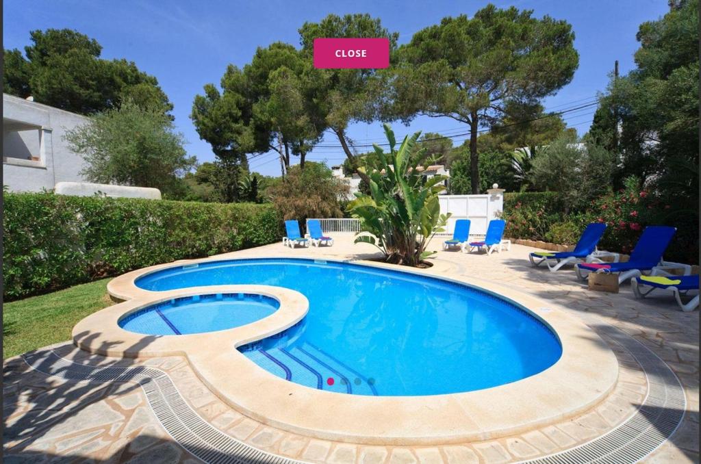 una piscina en un patio con sillas azules y árboles en Villa Marions, en Santanyí