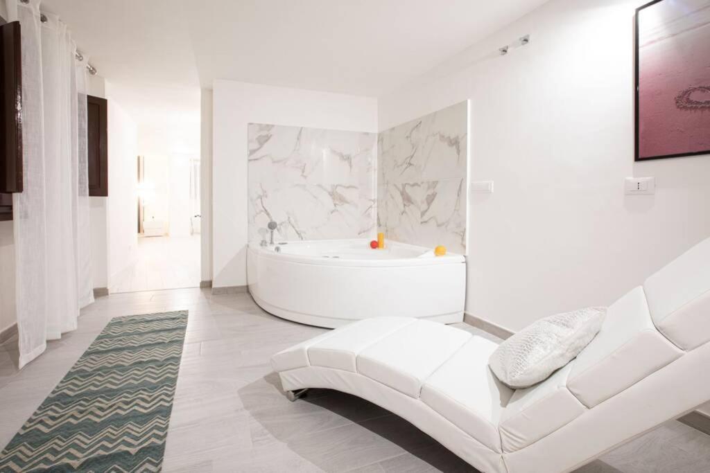 a white bathroom with a tub and a white couch at Unforgettable Split Level Jacuzzi Suite Navona - Top Collection in Rome