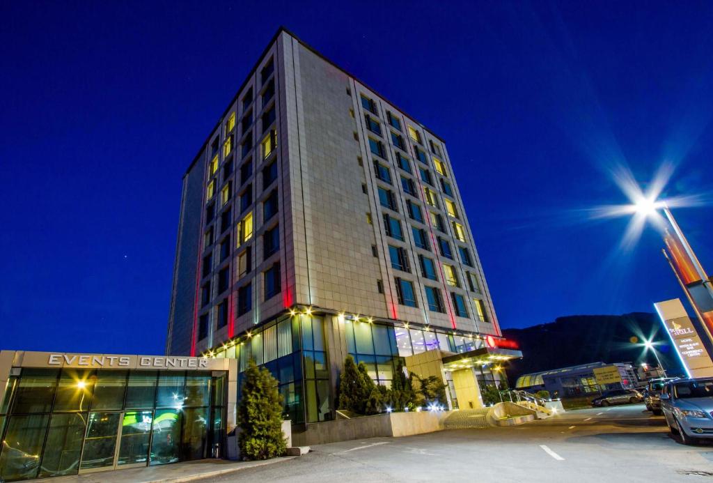 a tall building at night with a parking lot at Hotel HP Tower One Brasov in Braşov