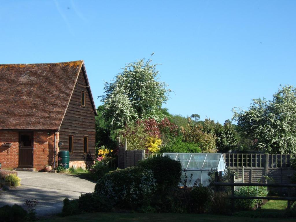 una casa vieja y un invernadero en un jardín en Snooky's Barn at Brook Cottage, en Graffham