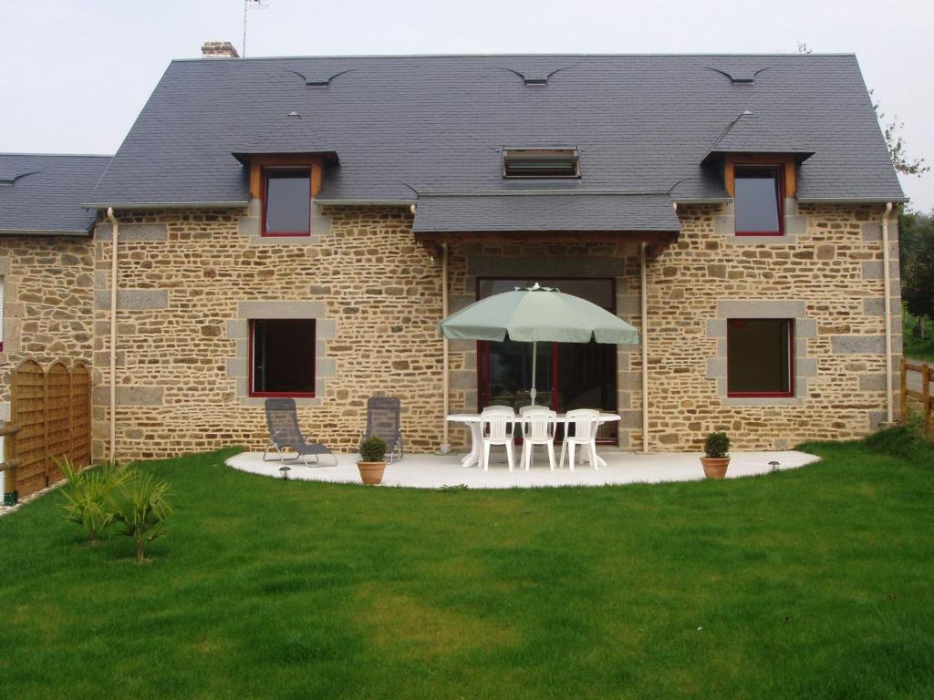 ein Backsteinhaus mit zwei Tischen und einem Regenschirm in der Unterkunft Modern Cottage in Normandy with Large Garden in Isigny-le-Buat