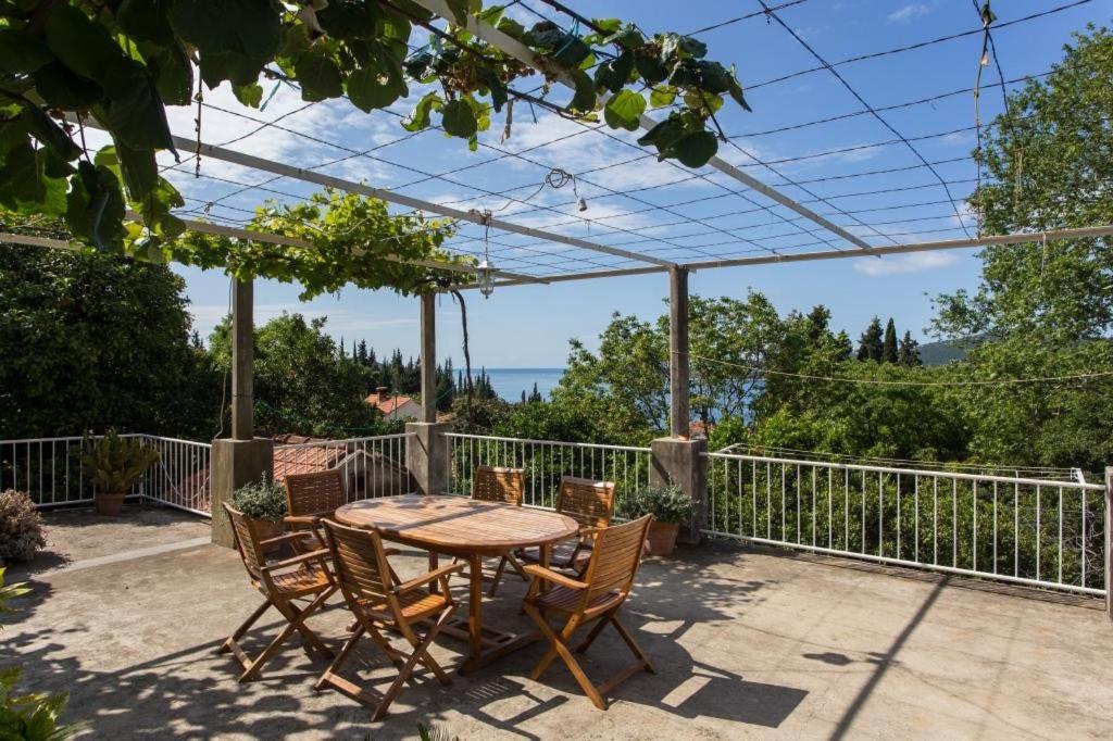 Une table et des chaises en bois sont disponibles sur la terrasse. dans l'établissement Apartments Anka, à Trsteno