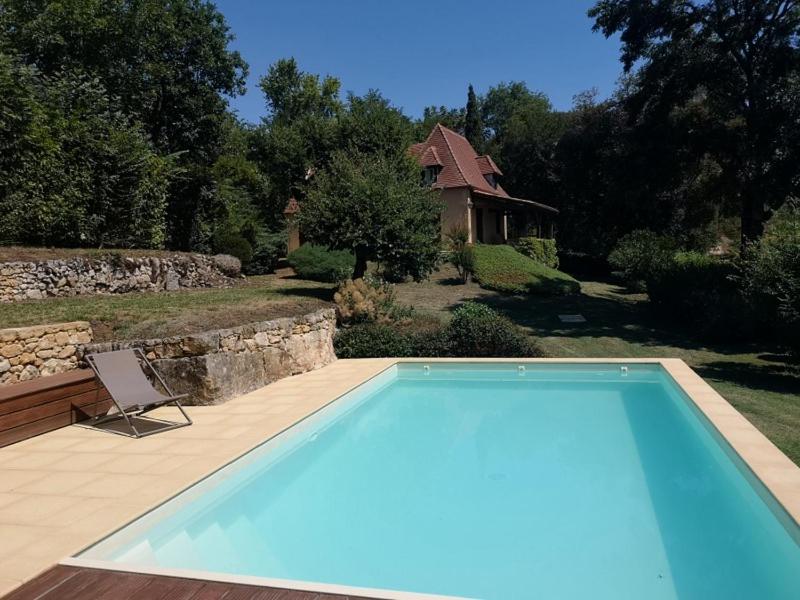 a swimming pool with a chair next to a house at Dans la bastide de Domme - piscine chauffée, parking privé in Domme