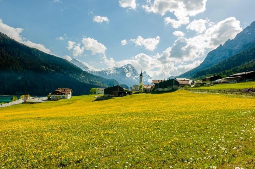a field of yellow flowers with a church in the background at Bio Yak Hof Heinz in Sufers