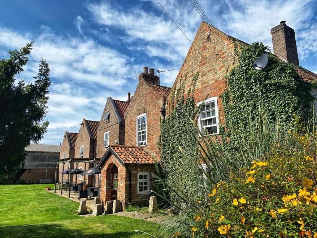 a large brick building with ivy growing on it at The Leagate Inn in Coningsby