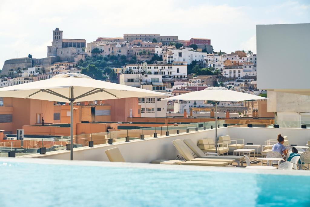 a pool on the roof of a building with umbrellas at El Puerto Ibiza Hotel Spa in Ibiza Town