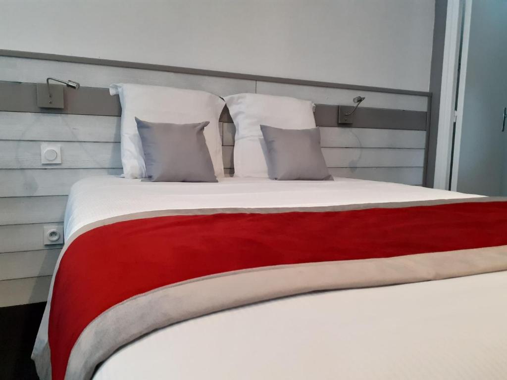 ein großes Bett mit roter und weißer Bettwäsche und Kissen in der Unterkunft Hôtel Akena Le Touquet-Camiers in Camiers