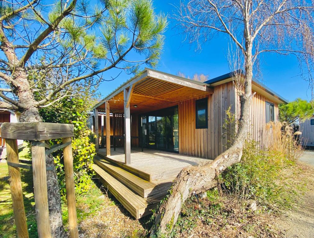 a home with a wooden porch and a tree at Camping Paradis 4 étoiles A La Corniche La Rochelle Angoulins in Angoulins-sur-Mer