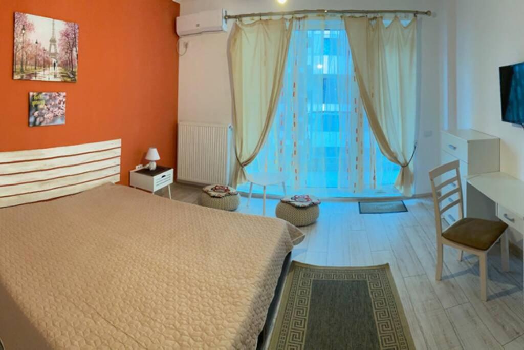 a bedroom with orange walls and a bed and a chair at SEAWAVE CAMPUS no parking in Constanţa