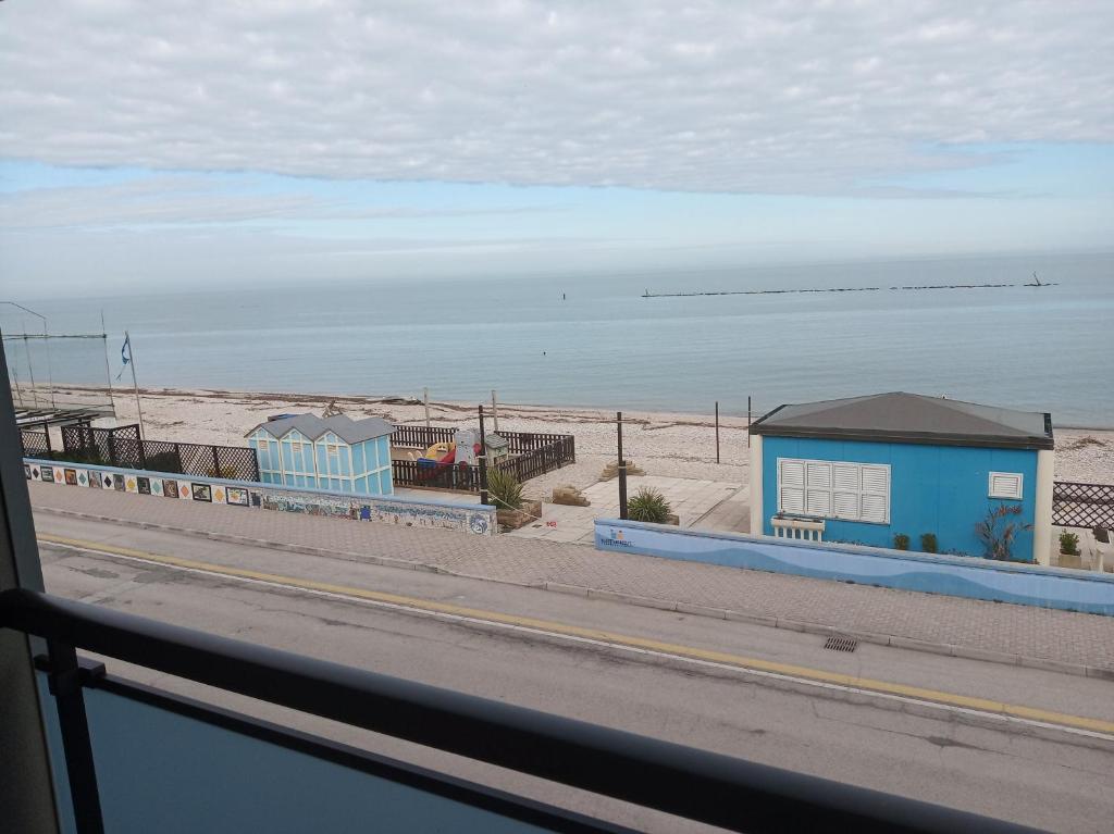 - une vue sur la plage avec un bâtiment bleu et l'océan dans l'établissement Fronte mare, à Marotta
