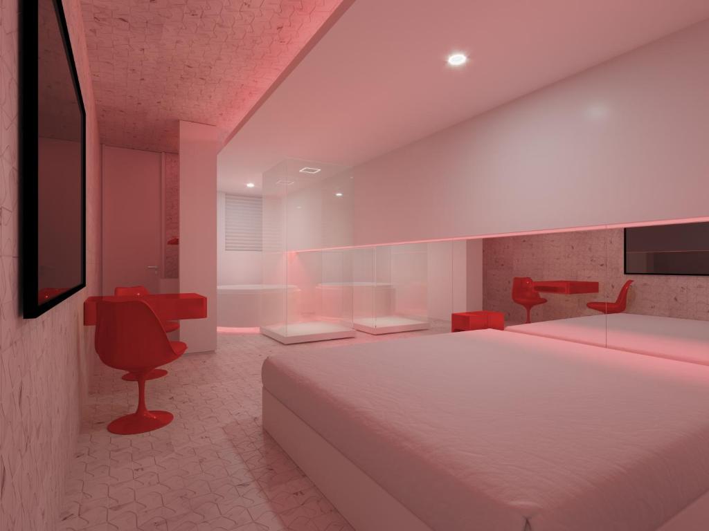 a bedroom with a white bed and red chairs at Motel Você Que Sabe (Adult Only) in Curitiba